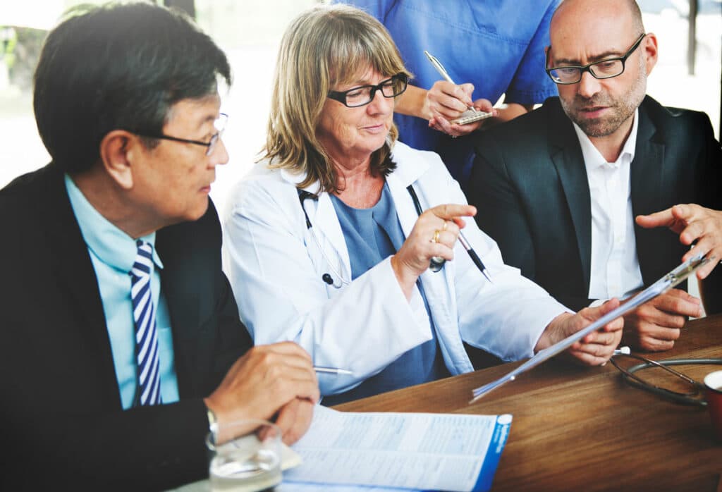 doctors and business men around a conference table discussing paperwork