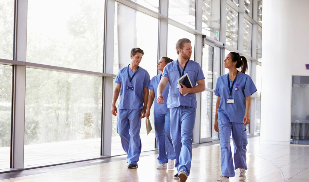 medical staff in blue scrubs walking down large hall