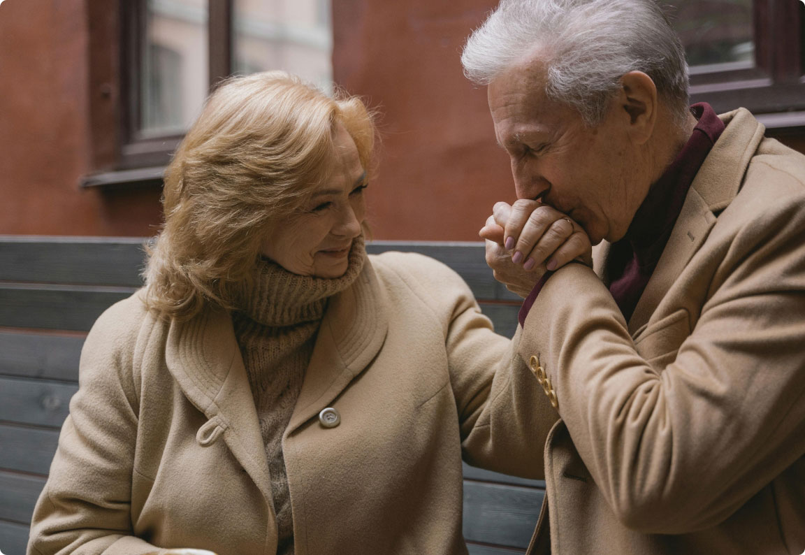 elderly couple where man is kissing his wife's hand